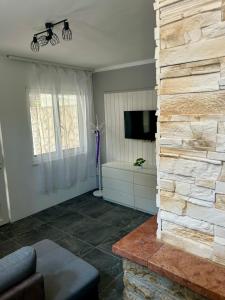 a living room with a stone wall and a tv at Fehér Villa in Kővágóörs