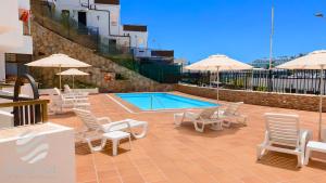 a patio with chairs and a swimming pool with umbrellas at Propiedad San Salvador in Mogán
