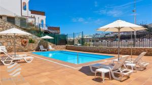 a pool with chairs and umbrellas on a patio at Propiedad San Salvador in Mogán +43 photos
