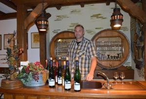 a man standing behind a counter with wine bottles at Ferienweingut Haus Christa in Briedern