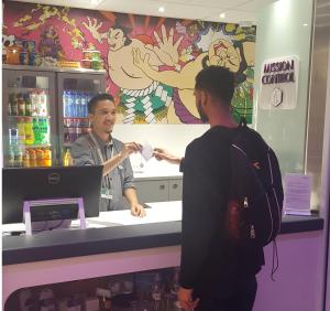 two men standing in front of a counter in a store at YOTELAIR Amsterdam Schiphol Transit Hotel in Schiphol