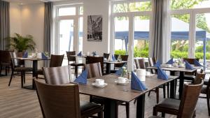a dining room with tables and chairs with blue napkins at Hotel Leitner in Kaufbeuren