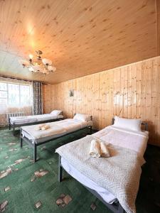 a room with three beds in a wooden wall at NURDAN Guest House Barskoon in Barskoon