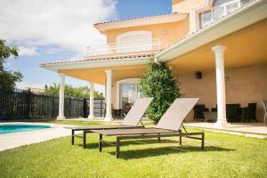 a pair of chairs sitting in the grass in front of a house at Ver Venir, acogedoras habitaciones con piscina in Garínoain