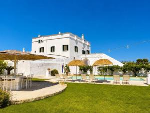 a building with chairs and umbrellas next to a pool at Masseria Mammella in Monopoli