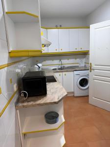 a small kitchen with white cabinets and a microwave at Gilarez in Estepona