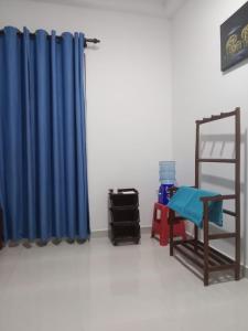 a room with a blue curtain and a chair and a shelf at Bosadi Guest House Katunayake in Katunayaka
