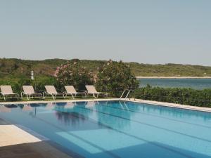 a swimming pool with chairs and a view of the water at Hotel Es Blau Des Nord in Colonia de Sant Pere