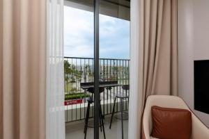 a room with a balcony with a table and a window at The Pathway Sầm Sơn in Sầm Sơn