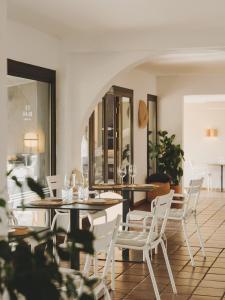 a dining room with tables and white chairs at Hotel Es Blau Des Nord in Colonia de Sant Pere