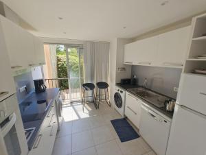a kitchen with white appliances and two stools in it at T4 proche de la plage & du centre in LʼÎle-Rousse
