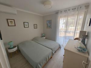 a white bedroom with a bed and a window at T4 proche de la plage & du centre in LʼÎle-Rousse