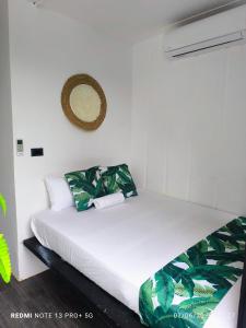 a bedroom with a bed with white sheets and green leaves at Tucan container in Fortuna