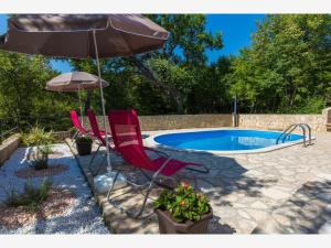 two chairs and an umbrella next to a swimming pool at Apartment Ivana in Crikvenica