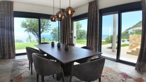 a dining room with a table and chairs and large windows at Villa Adria Heights in Pečurice