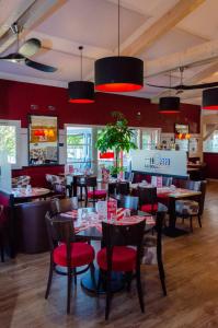 a restaurant with red walls and tables and chairs at Contact Hôtel Fontenay le Comte in Fontenay-le-Comte