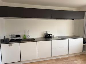 a kitchen with white cabinets and a black counter top at 24 h chek in big house in Copenhagen +21 photos