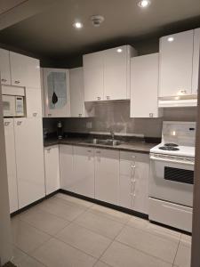 a white kitchen with white cabinets and appliances at Auberge l'Ambassadeur in Amqui
