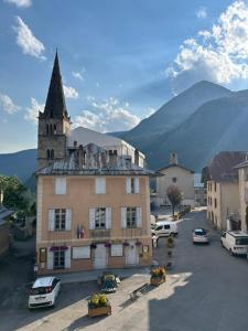 a building with a tower and a church with mountains in the background at Chambres d'hôtes de l'encabanée in Saint-Paul