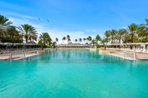 a large swimming pool with palm trees and chairs at Mangrove Beach Corendon Curacao All-Inclusive Resort, Curio by Hilton in Willemstad