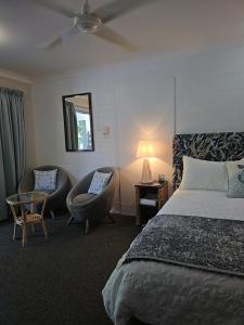 a bedroom with a bed and a chair and a mirror at Bramston beach resort in Bramston Beach