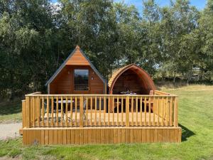 a wooden cabin in a field with a fence at Hill View Glamping Hut in Tregaron