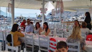 a group of people sitting at tables in a marquee at To Spitaki House in Perdika