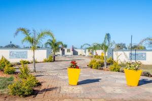 two large yellow pots with flowers in them on a sidewalk at KGADITSE ROAD LODGE in Moletlane