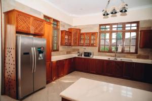 a kitchen with a stainless steel refrigerator and wooden cabinets at Kilimanjaro pazuri summit villas 1 in Msaranga