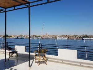a balcony with two chairs and a view of the water at Nile Castle in Luxor