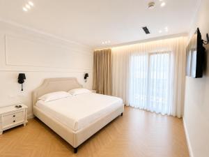 a white bedroom with a bed and a television at Hotel Luxury Palace in Ishull-Lezhë