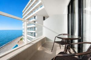 a balcony with a table and chairs and the ocean at Mayak Bamboo Beach Apartments in Kobuleti