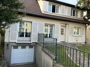 a house with a white garage door and a fence at Spacieuse et agréable à séjourner in Garges-lès-Gonesse