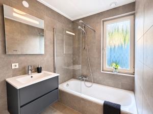 a bathroom with a tub and a sink and a shower at Weidezicht in Ermelo
