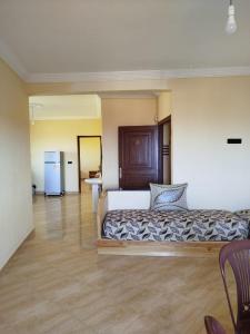 a bedroom with a bed and a kitchen with a refrigerator at Résidence Nydia in Ras El Ma