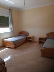 a bedroom with two beds and a window at Résidence Nydia in Ras El Ma