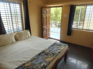 a bedroom with a bed and a door to a balcony at Swarna Lodge in Badami