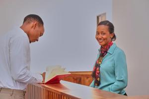 a man and a woman are standing at a desk at Villa Maisha in Arusha
