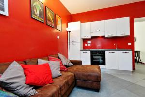 ローマにあるCozy Apartment Fabia 300 mt from Colosseumの赤い壁のリビングルーム(茶色のソファ付)