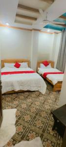 a bedroom with two beds with red pillows on them at Ruby Bahrain Hotel in Mingāora