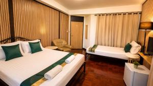 a hotel room with two beds and a television at Cocohouse Sukhumvit 1 in Makkasan