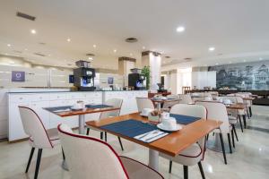 a restaurant with tables and chairs and a kitchen at Crisol Leganés in Leganés