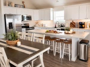 a kitchen with white cabinets and a large island with bar stools at Beachfront Luxe, Ocean Views, Hot tub, Firepit, Sleeps 14 in Bolivar Peninsula