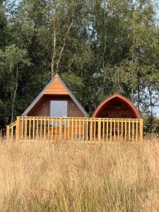 a small cabin with a fence in a field at Meadow View Glamping Hut in Tregaron