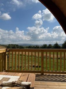 a wooden deck with a table and a view of a field at Meadow View Glamping Hut in Tregaron +5 photos