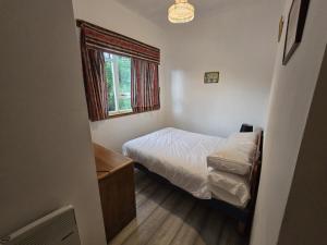 a small bedroom with a bed and a window at The Garve Flats in Garve