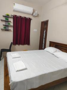 a bedroom with a white bed with a red curtain at Kavitha Residency in Virudunagar