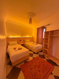a bedroom with two beds and a checkered floor at Mira Guest House in Taghazout