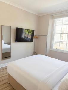 a bedroom with a white bed and a flat screen tv at Central Room to Rent in Plymouth