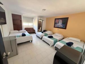 a hotel room with four beds and a couch at Hotel Exito Barranquilla in Barranquilla
